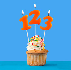 Orange candle number 123 - Birthday cupcake on blue background