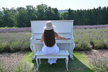 girl in white dress on lavender field sits with her back to piano, © Галина Миронюк
