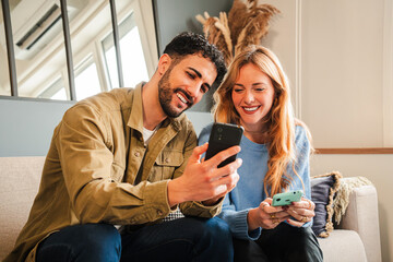 Happy couple enjoying time together, sharing a moment while looking at their smartphones with...