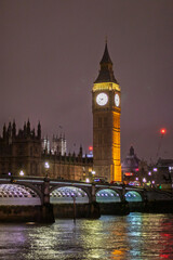Fototapeta premium A stunning view of Big Ben and Westminster Bridge illuminated against the night sky, with reflections shimmering on the Thames River. The iconic London landmark showcases