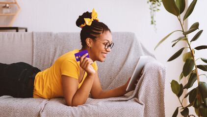 Online Shopping Concept. Happy Black Woman In Glasses Holding And Using Digital Tablet And Credit...