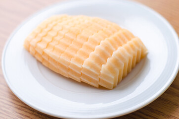 Sliced Cantaloupe on a white plate a top a wooden table