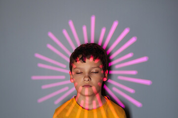 Portrait of a white boy with dark hair in studio, standing with closed eyes and reflection of...