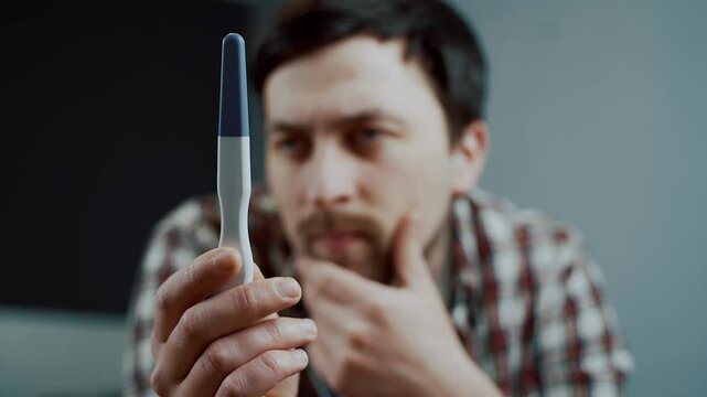 A man stares at a pregnancy test handed to him by his wife, holding his head in frustration. His emotions reflect disappointment and concern, clearly showing his unease about the unplanned pregnancy. 