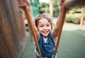 smiling child climbing at ropes on playground