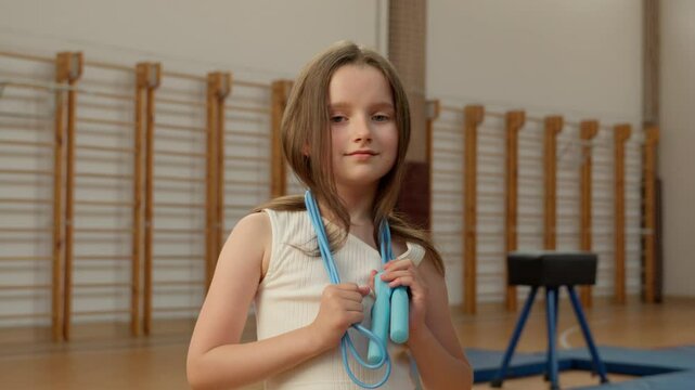 Little Caucasian girl with skipping rope child kid pupil schoolgirl sport lesson physical education training exercise acrobat gymnast school gym sportswoman teenager workout learner classroom student