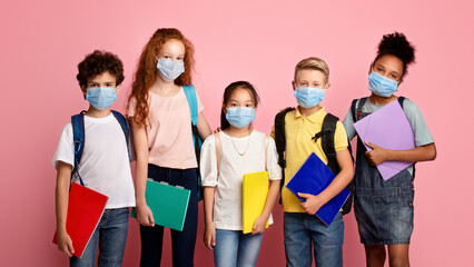 Health care and education concept. Portrait of schoolchildren wearing protective masks against pink background