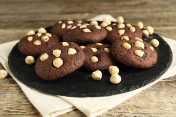 Tasty chocolate cookies with hazelnuts on wooden table, closeup