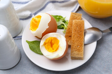 Soft boiled eggs with bread on grey table, closeup