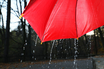 Open red umbrella under pouring rain outdoors, closeup