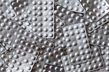 Medical drugs and pills in silver shiny package full frame background. Top view. Medicine and healthcare concept