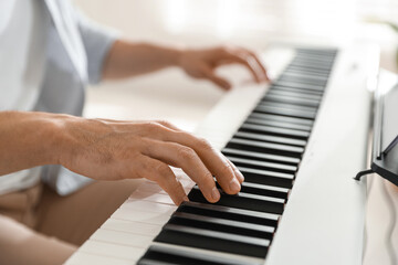 Man playing synthesizer indoors, closeup. Electronic musical instrument