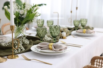 Color accent table setting with glasses, flowers and green napkins indoors, closeup