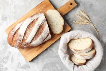Wooden cutting board with fresh bread and spikes on grey table, flat lay