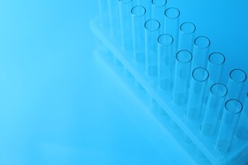 Empty test tubes on light blue background, space for text. Laboratory glassware