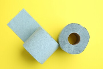 Light blue toilet paper roll on yellow background, top view