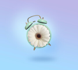 Spring time. Alarm clock with flower instead of dial on light blue gradient background