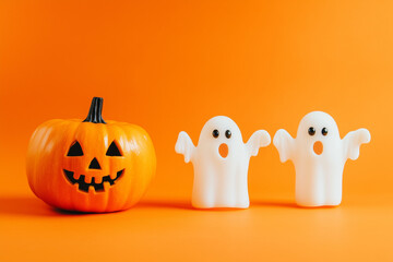 Halloween ghosts with funny pumpkin isolated on an orange background