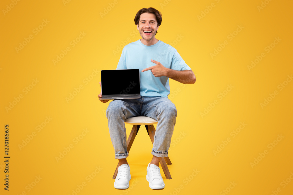 Poster Check This Great Website. Portrait of happy guy holding pc in hand and pointing finger at laptop with black blank screen, showing device with empty free space for mock up, presenting notebook