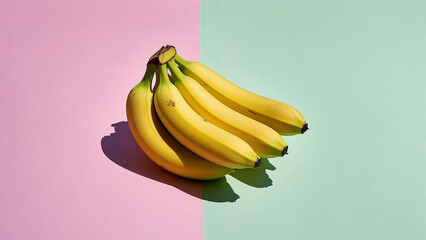 A bunch of ripe yellow bananas sits against a split backdrop of pastel pink and green.
