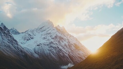 Majestic snow-capped mountains at sunset with golden light illuminating the valley below