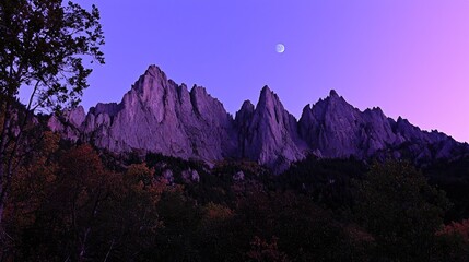 Majestic mountain range under a twilight sky with a crescent moon illuminating the peaks