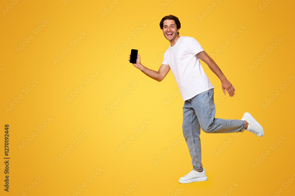 Poster cool mobile offer ad. joyful young casual guy showing empty cell phone screen jumping up in the air 