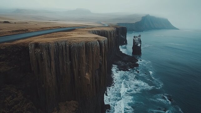 A scenic coastal road with cliffs on one side and the ocean on the other, with vast open skies.