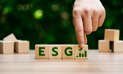 Hand arranging wooden blocks with ESG letters, representing environmental, social, governance...