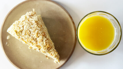 This photograph features a close-up of a slice of Napoleon cake with delicate, flaky layers and...