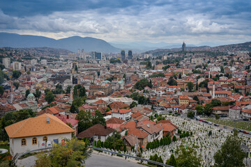 Fototapeta premium Cityscape view of urban area with buildings rooftops mountains and cloudy skies in the background