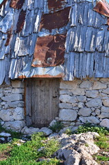 Rustic wall of stone wood and aged metal showing weathered textures and natural elements combined