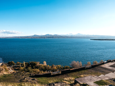 Beautiful autumn view with blowing wind at Lake Sevan, landscape on the hill near Sevanavank Monastery, blue water with mountains on open blue sky background, Armenia country.