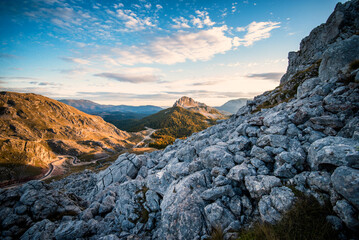 Mountain vista of rocky landscape under blue sky with sparse clouds featuring valley and distant peaks
