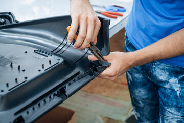 Repairing a component: hands using pliers to fix a black plastic part Focus on the repair process
