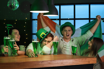 Group of drunk young people with beer celebrating St. Patrick's Day at counter in pub