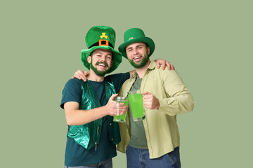 Young men in leprechaun hats with green beards holding glasses of beer on green background. St....