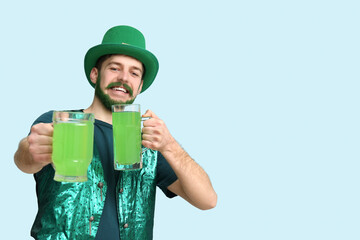Young man in leprechaun hat with green beard holding glasses of beer on blue background. St....