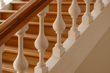 Fototapeta premium Luxurious wooden staircase with white balusters. The balusters are tall and thin, which gives the staircase a classic and elegant look.