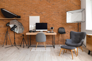 Photographer workplace with computer, photo cameras and lighting equipment in modern studio