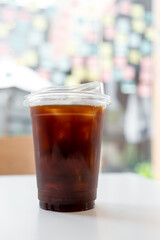 A take away plastic cup of iced black coffee