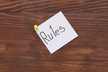 Pinned paper with word RULES on wooden background