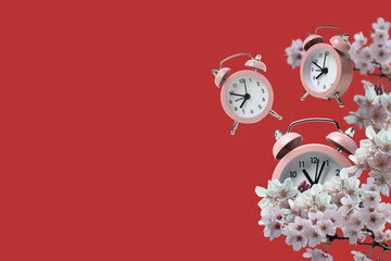 Spring Forward. Pink alarm clocks on a red background, with flowers, with space for text.
