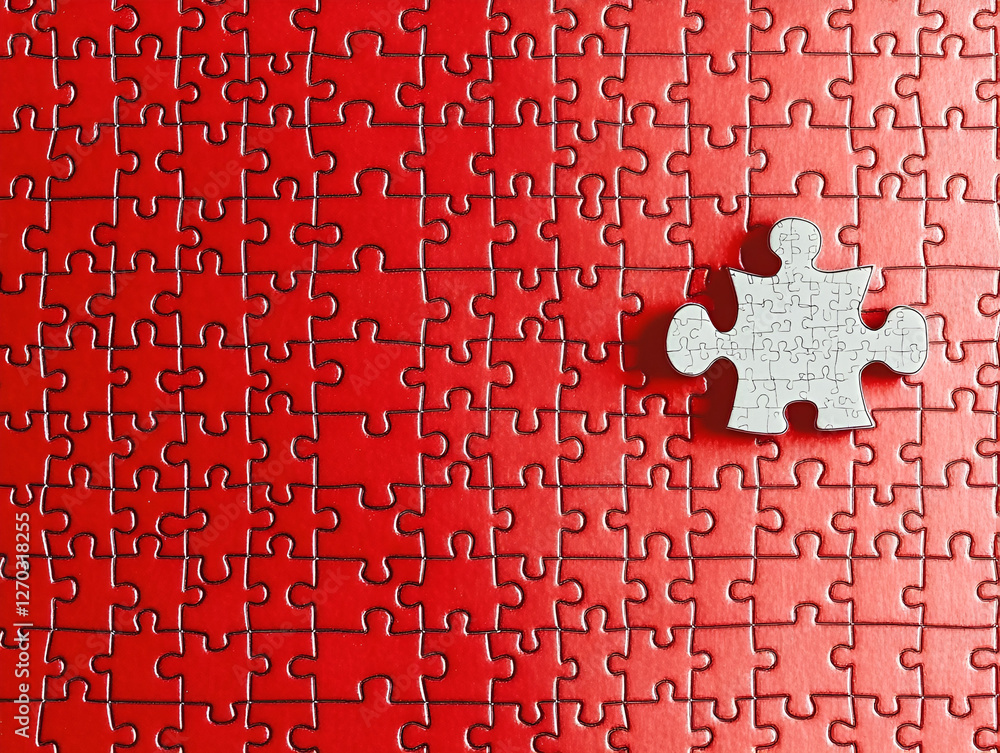 Poster puzzle of problem solving: a single, unattached piece rests on a partially assembled red puzzle, sym