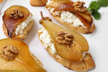 Pear bruschetta with ricotta cheese and walnuts on tray, closeup