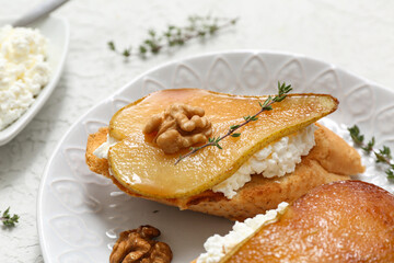 Plate of pear bruschetta with ricotta cheese, walnuts and thyme on white background, closeup