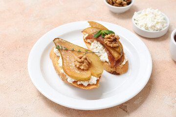 Plate of pear bruschetta with ricotta cheese and walnuts on beige background