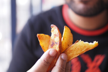 Crispy potato wedges held in hand at a casual dining spot