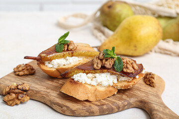 Wooden board of pear bruschetta with ricotta cheese, walnuts and mint on white table