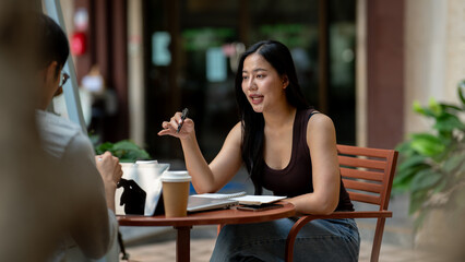 A gorgeous, confident Asian woman having an informal meeting with her colleague at a cafe.